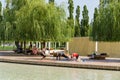 Rest area `Embankment` with artificial water reservoir. Young women are engaged in gymnastics in willow shade.