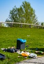 Rest area in a park on which people have thoughtlessly throw their trash next to the trash can on the lawn