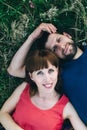 Couple makes a selfie while lying on the grass in flowers. Rest, lovers on a flower meadow. Bearded man and a girl in a red dress Royalty Free Stock Photo