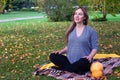 Rest for pregnant mothers. Beautiful young pregnant woman sitting on grass in park in lotus pose doing breathing exercises. Royalty Free Stock Photo