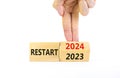 2024 restart new year symbol. Businessman turns a wooden cube and changes words Restart 2023 to Restart 2024. Beautiful white
