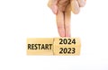 2024 restart new year symbol. Businessman turns a wooden cube and changes words Restart 2023 to Restart 2024. Beautiful white