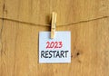 2023 Restart symbol. White paper with words 2023 Restart, clip on wooden clothespin. Beautiful wooden background. Business and