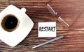 RESTART text on the sticky with coffee,pen and glasses on the wooden background Royalty Free Stock Photo