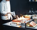 Restaurant Chef cook preparing salmon filet flambe in open kitchen Royalty Free Stock Photo