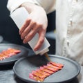 Restaurant Chef cook preparing tuna striped filet and pouring fish with oil sause