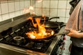 Restaurant Chef cooking with flame in a frying pan on a kitchen stove Royalty Free Stock Photo