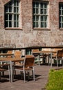 Restaurant, coffee shop or bar terrace or patio with tables and chairs in the sunshine. Furniture is made of wood and metal. Brick Royalty Free Stock Photo