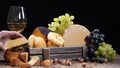 Restaurant craft cheese . Variety of hard cheese put in a beautifully composition. Wine is pouring into a flass in slow