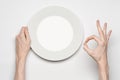 Restaurant and Food theme: the human hand show gesture on an empty white plate on a white background in studio isolated top view