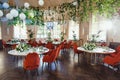 restaurant hall with white tables and red exquisite chairs, decorated with floral arrangements on the tables, homemade exotic Royalty Free Stock Photo