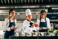 In a restaurant kitchen a senior Asian chef educates multiracial students