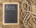 Restaurant menu. Top view of chalkboard menu laying on very old burlap background with copy space Royalty Free Stock Photo
