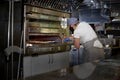 Restaurant professional open kitchen, Woman in a mask on her face, preparing pizza, new measures to fight the virus