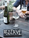 Restaurant reserved table sign. Bottle and glass of white wine and beer on table