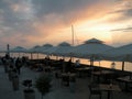 Restaurant by the sea with sunset, people at dinner, tables under white umbrellas.Mediteranean scene of holiday and turists enjoy