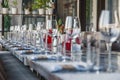 Restaurant serving, glass wine and water glasses, forks and knives on textile napkins stand in a row on a gray wooden table. Royalty Free Stock Photo