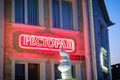 Restaurant sign in red neon on the background of the statue of Pavlik and the night sky