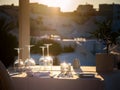 Restaurant table decorated with glasses on terrace in sunset light on the island Santorini Royalty Free Stock Photo