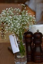 Restaurant table decoration: baby breath flower in the glass vase with note paper, brown wooden salt and pepper shakers Royalty Free Stock Photo