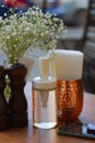 Restaurant table decoration outdoors: baby breath flower in the glass vase, brown wooden salt and pepper shakers, sanitizer. Royalty Free Stock Photo