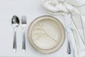 Tableware and silverware setting on white tablecloth, top view Royalty Free Stock Photo