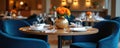Restaurant table setting with modern design. The photo shows a round table with floral decor. Blue chairs complement the Royalty Free Stock Photo