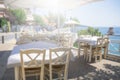 Restaurant tables and chairs below the sunshade on the terrace on the seashore. Blurred scene of the restaurant in Neos marmaras, Royalty Free Stock Photo