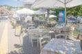 Restaurant tables and chairs below sunshades on the terrace on the seashore. Blurred scene of the restaurant in Neos marmaras, Royalty Free Stock Photo