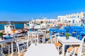 Restaurant tables and fishing boats anchoring in Naoussa port, Paros island, Greece Royalty Free Stock Photo