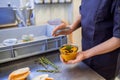 Restaurant worker holding souse in a bowl in kitchen