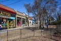 Restaurants and shops along a sidewalk with people, bare winter trees, lush green plants tall black light posts Royalty Free Stock Photo