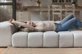 Rested woman stretching lying on sofa in living room