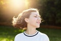 Restful attractive young female closing her eyes with pleasure admiring sunset and fresh air outdoor. Beautiful woman with waved h Royalty Free Stock Photo