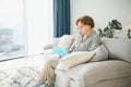 Restful reading. Portrait of thoughtful aged woman reading favorite literature at cozy home. She is lying on pillows on Royalty Free Stock Photo