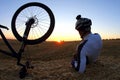 Resting cyclist with a Bicycle looks at sunset
