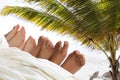 resting legs of people against the background of palm branches. resort relaxation on the beach. many children feet peeking from Royalty Free Stock Photo