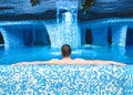 Resting man lies and relaxes in the pool.Guy is relaxing in the jacuzzi Back view. Adult man lying in the pool and