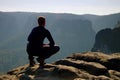 Resting man at the top of rock with aerial view of the deep misty valley bellow Royalty Free Stock Photo