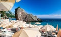 Resting people on pebble public stone beach with beautiful puff rocks. Rafailovici, Montenegro