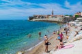 Resting people on the sandy Pizana beach against the background of the fortress walls of the citadel of the old town of Budva.