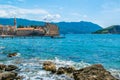 Resting people swim near the fortress walls citadel. Landscape of old town Budva and St Nicholas Stevi Nikola beach on Skolj