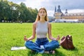 Teenage girl student meditating sitting on grass, educational building background Royalty Free Stock Photo