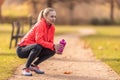 A resting sportswoman holds a plastic bottle with a drink in her hand after running in the park Royalty Free Stock Photo