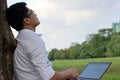 Resting time. Asian young man looking at the sky after work against his laptop. Royalty Free Stock Photo
