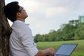 Resting time. Asian young man looking at the sky after work against his laptop.