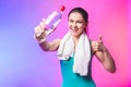 Resting time. Sporty girl with bottle of water and towel on her shoulders. Photo of fitness model isolated on white background. Royalty Free Stock Photo