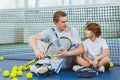 Resting young man or tennis coach with boy sitting near net