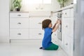 Restless little hispanic boy watching cake baking in the oven, crouching down in the kitchen Royalty Free Stock Photo