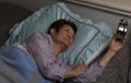 Restless senior woman glaring at alarm clock during nighttime while in bed